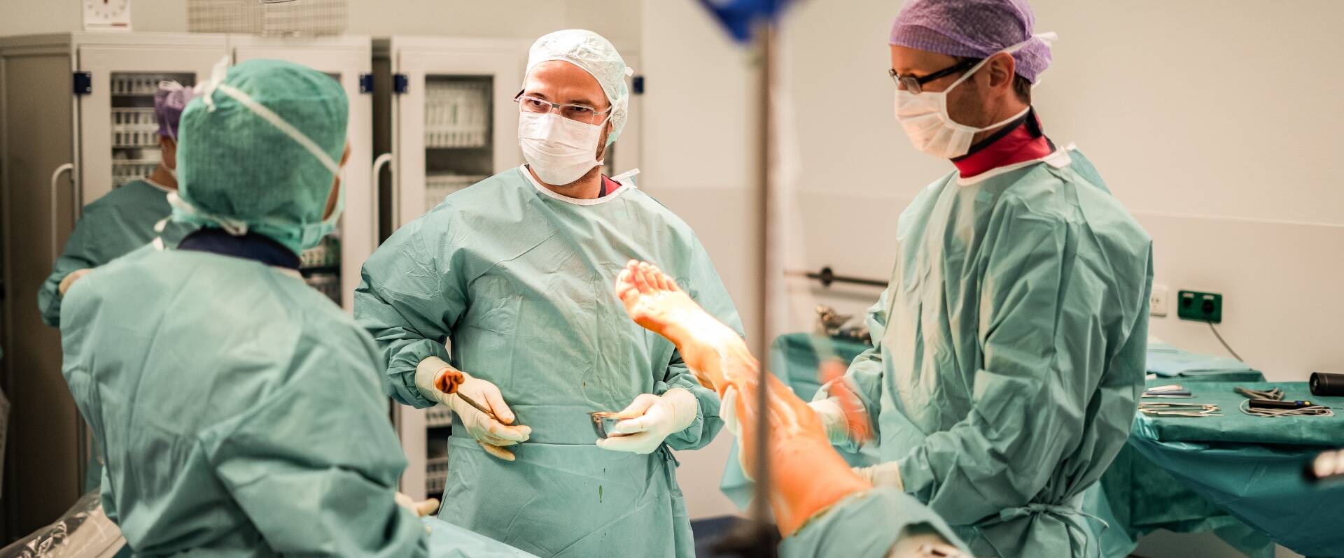 Drei Ärzte in OP-Kleidung und Mundschutz des Endoprothetikzentrums Orthopädie besprechen sich im OP 