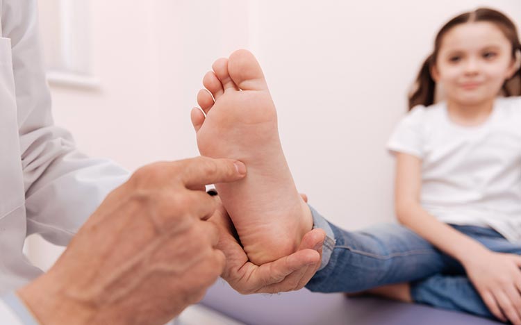 Kinder- und Jugendorthopädie - Kind streckt Fuß Arzt entgegen