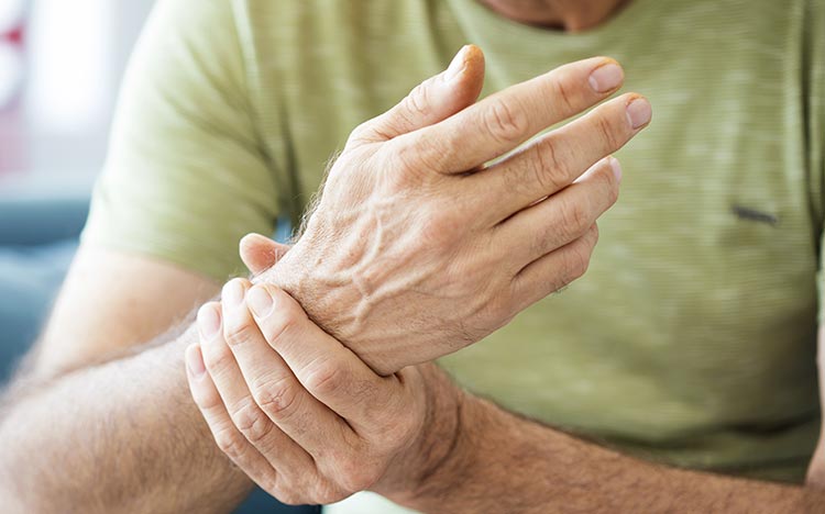Rheumatische Erkrankungen - Mann hält sich Handgelenk